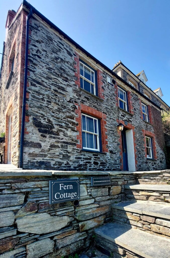 a stone and brick cottage named 'Fern Cottage" seen from below